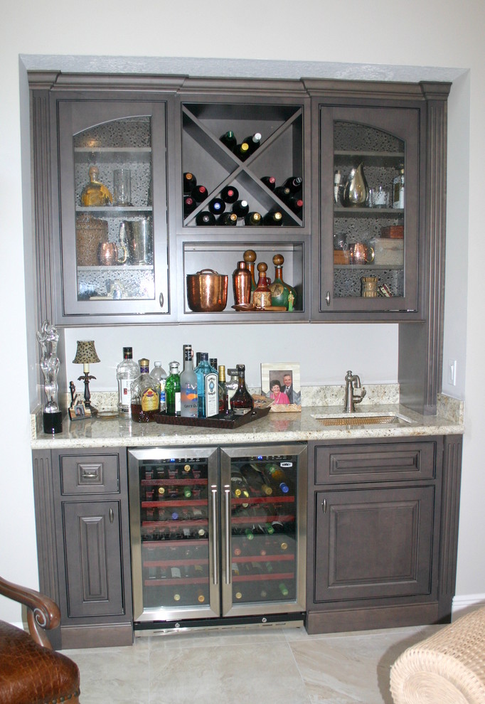 This is an example of a mid-sized transitional home bar in Miami with an undermount sink, beaded inset cabinets, grey cabinets, granite benchtops, beige splashback, stone tile splashback and porcelain floors.