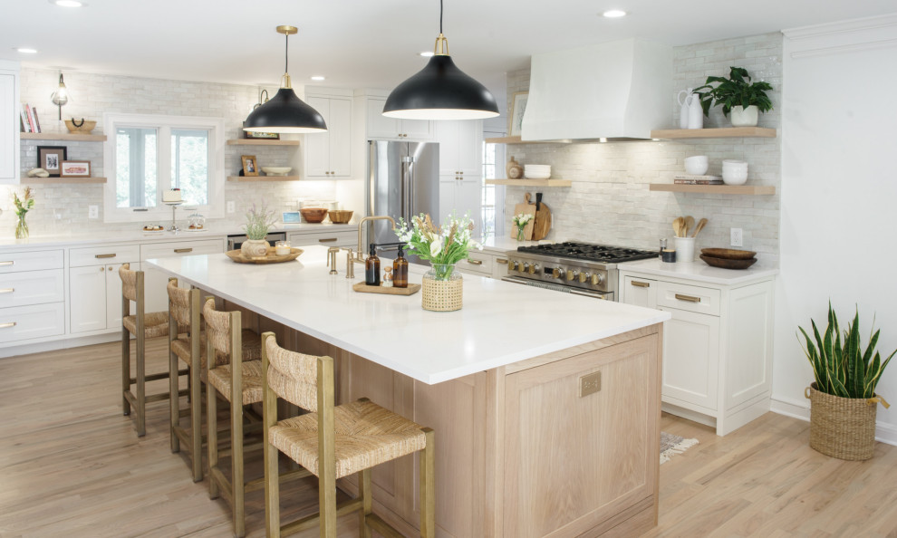 Photo of a large transitional l-shaped eat-in kitchen in Atlanta with an undermount sink, shaker cabinets, quartz benchtops, stone tile splashback, stainless steel appliances, light hardwood floors, with island, beige floor, white benchtop, white cabinets and beige splashback.