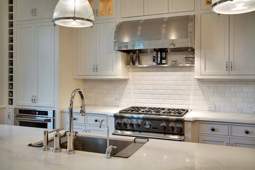 Inspiration for a mid-sized transitional single-wall dark wood floor and brown floor eat-in kitchen remodel in Minneapolis with an undermount sink, shaker cabinets, white cabinets, quartz countertops, white backsplash, subway tile backsplash, stainless steel appliances and an island