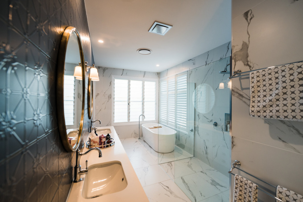 This is an example of a traditional bathroom in Melbourne with a freestanding tub, black tile, marble floors, an undermount sink, white floor and white benchtops.