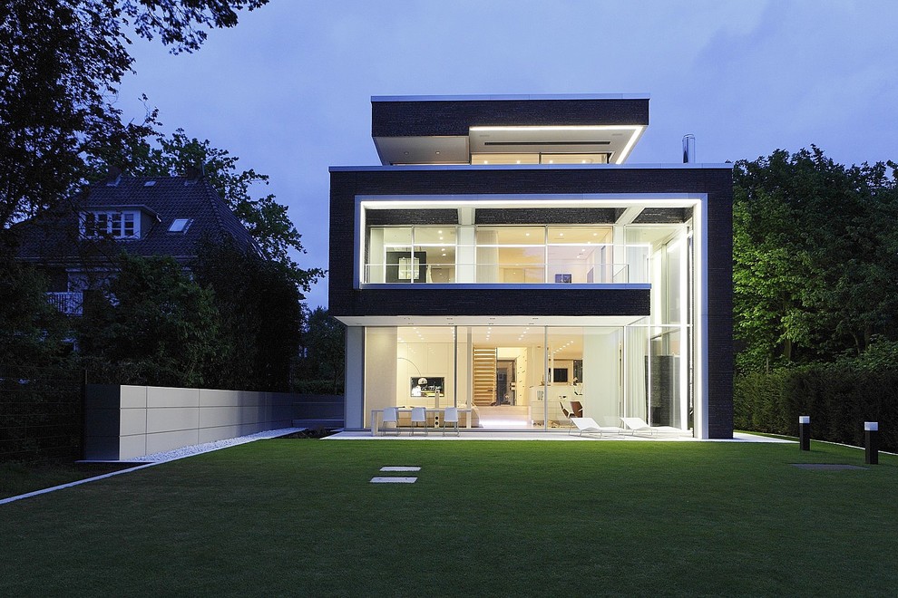 This is an example of a large contemporary three-storey black exterior in Dortmund with mixed siding and a flat roof.