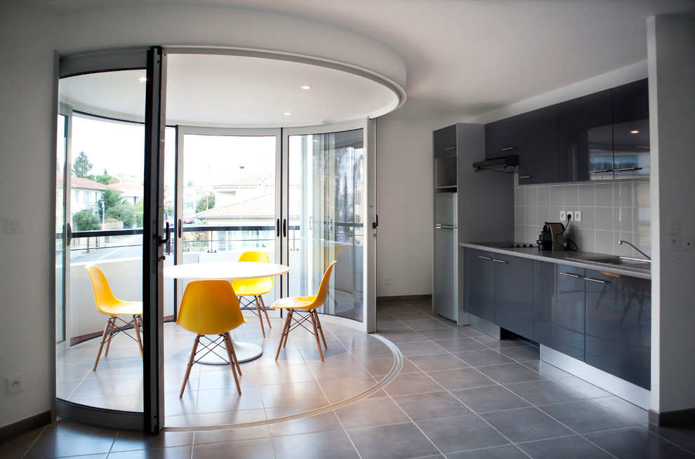 This is an example of a mid-sized modern single-wall open plan kitchen in Lyon with a drop-in sink, black cabinets, grey splashback, ceramic splashback, ceramic floors and no island.