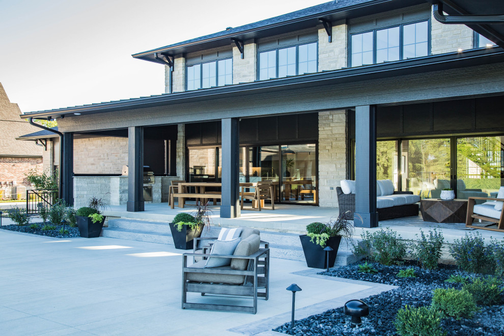 Idées déco pour un très grand porche d'entrée de maison arrière moderne avec une cheminée, une dalle de béton et une extension de toiture.