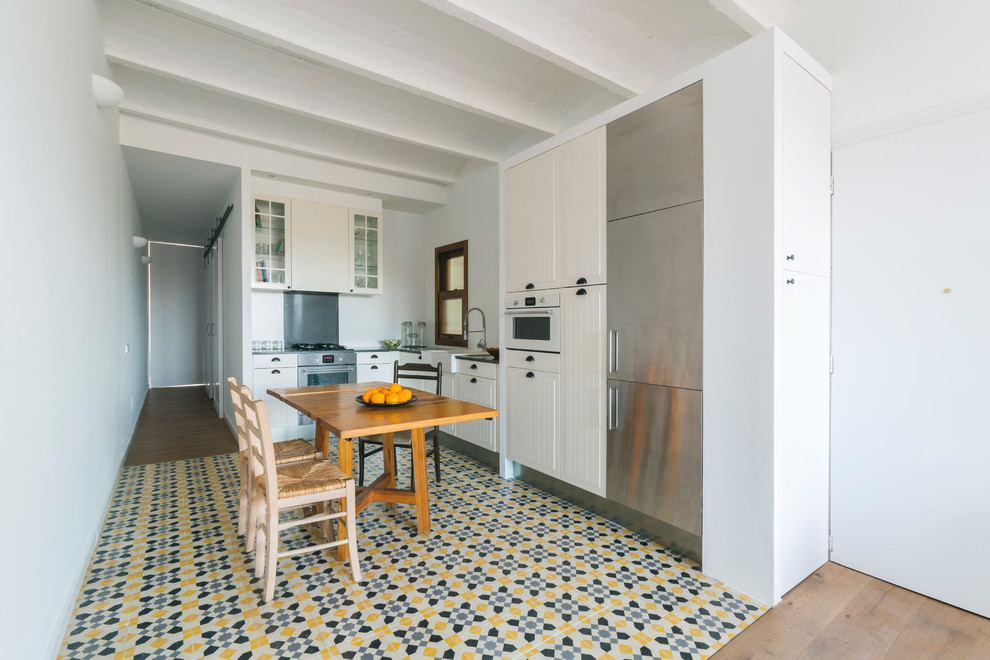This is an example of a mid-sized scandinavian l-shaped eat-in kitchen in Barcelona with a farmhouse sink, beige cabinets, stainless steel appliances, white splashback, ceramic floors and no island.