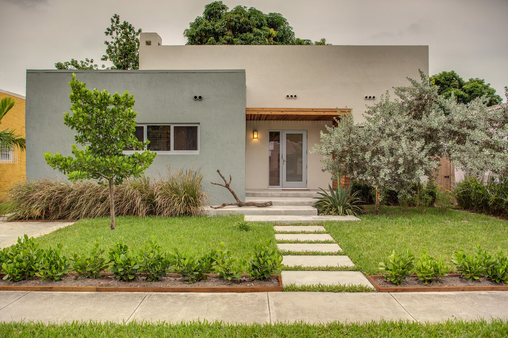 This is an example of a contemporary one-storey stucco beige house exterior in Miami with a flat roof.