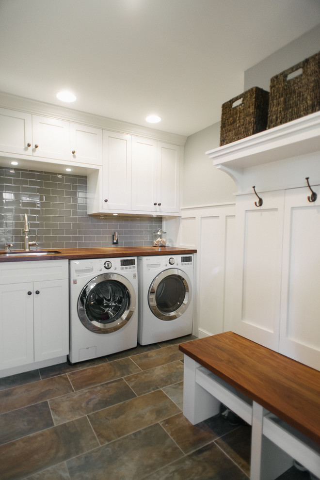 Design ideas for a mid-sized arts and crafts l-shaped utility room in Detroit with an undermount sink, white cabinets, wood benchtops, grey walls, porcelain floors, a side-by-side washer and dryer and shaker cabinets.