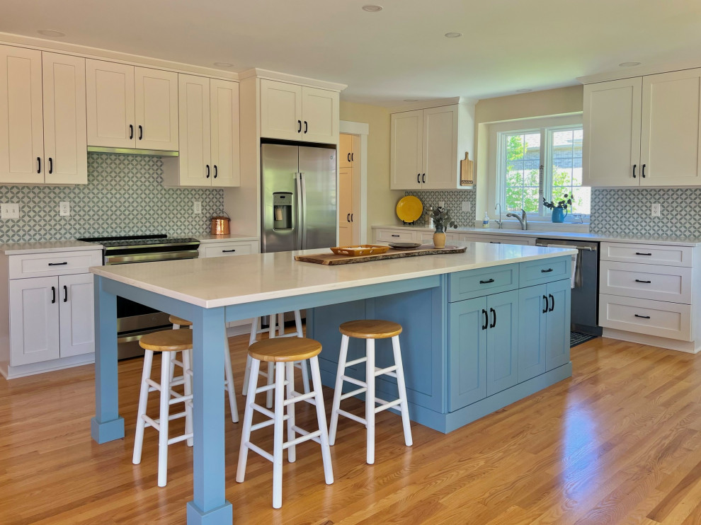Example of a light wood floor and brown floor eat-in kitchen design in Chicago with recessed-panel cabinets, blue cabinets, quartz countertops, blue backsplash, ceramic backsplash, stainless steel appliances, an island and white countertops