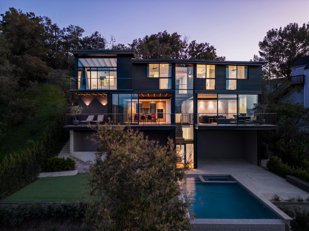 Inspiration for a large contemporary two-storey black house exterior in Los Angeles with wood siding, a butterfly roof, a mixed roof, a black roof and clapboard siding.