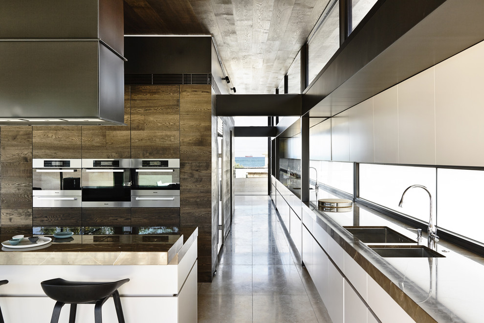 Contemporary kitchen in Melbourne with a double-bowl sink, white cabinets, stainless steel appliances, limestone floors and with island.
