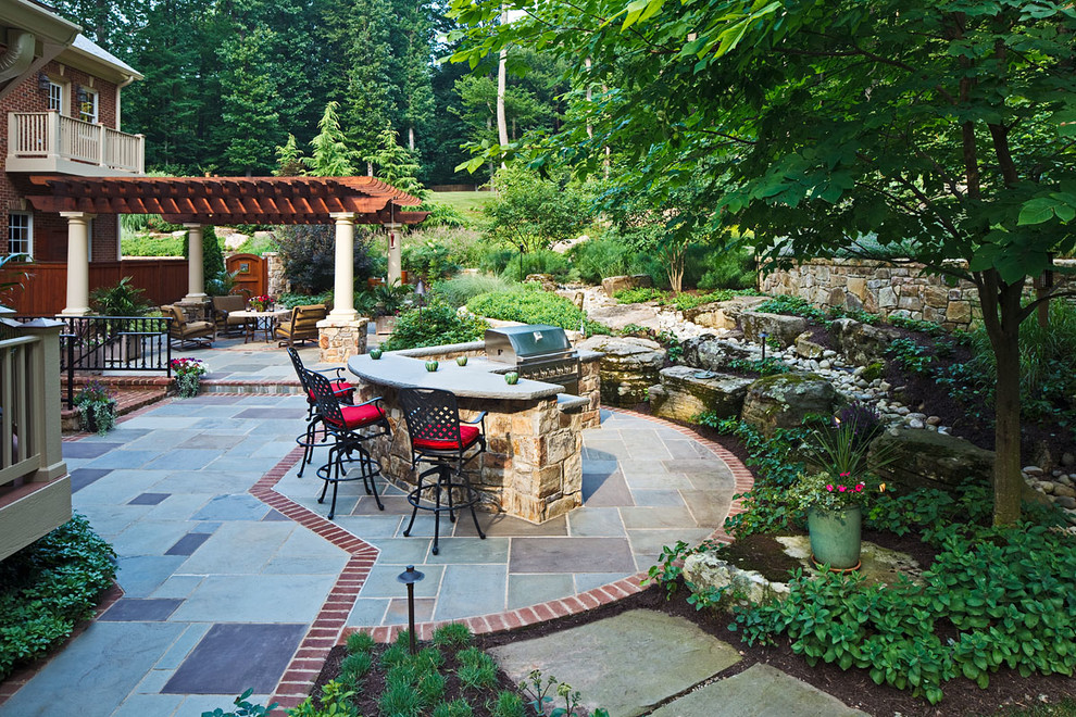 This is an example of a mid-sized country backyard patio in DC Metro with natural stone pavers.