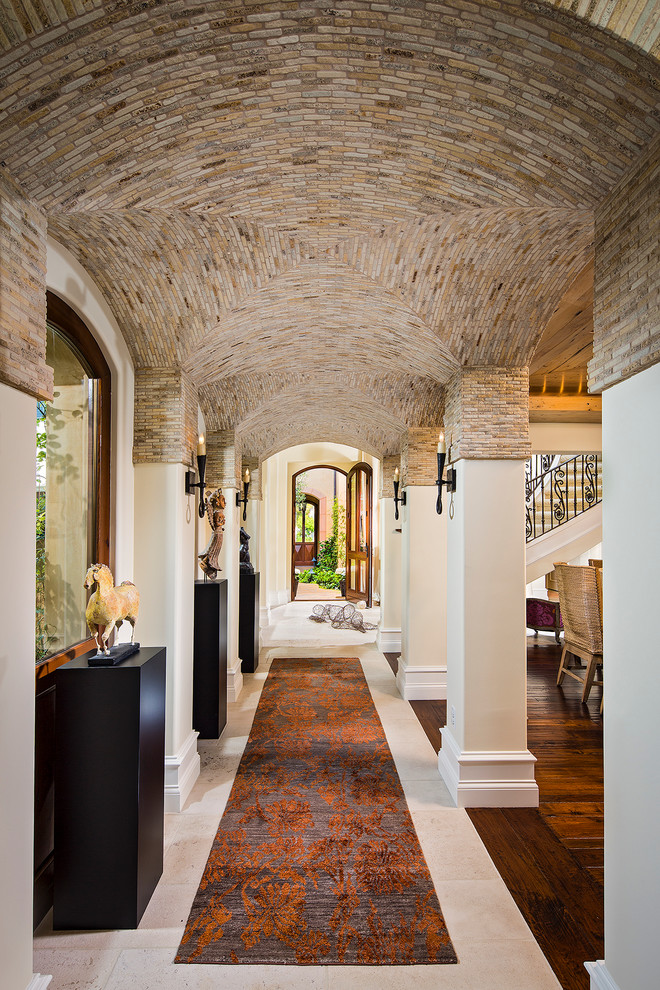 This is an example of an expansive mediterranean hallway in Orange County with beige walls and travertine floors.
