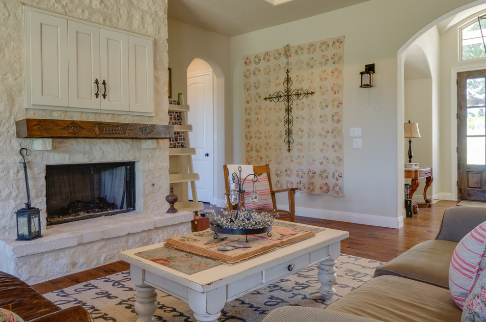 Country living room in Austin with white walls, medium hardwood floors, a standard fireplace and a brick fireplace surround.