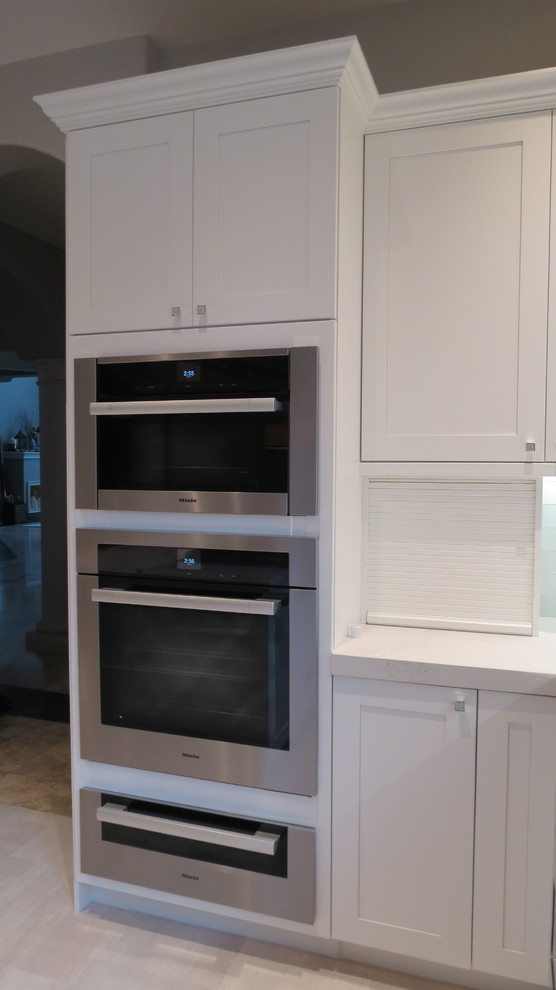 Enclosed kitchen - large transitional l-shaped light wood floor and beige floor enclosed kitchen idea with a double-bowl sink, shaker cabinets, white cabinets, marble countertops, blue backsplash, glass tile backsplash, stainless steel appliances and an island