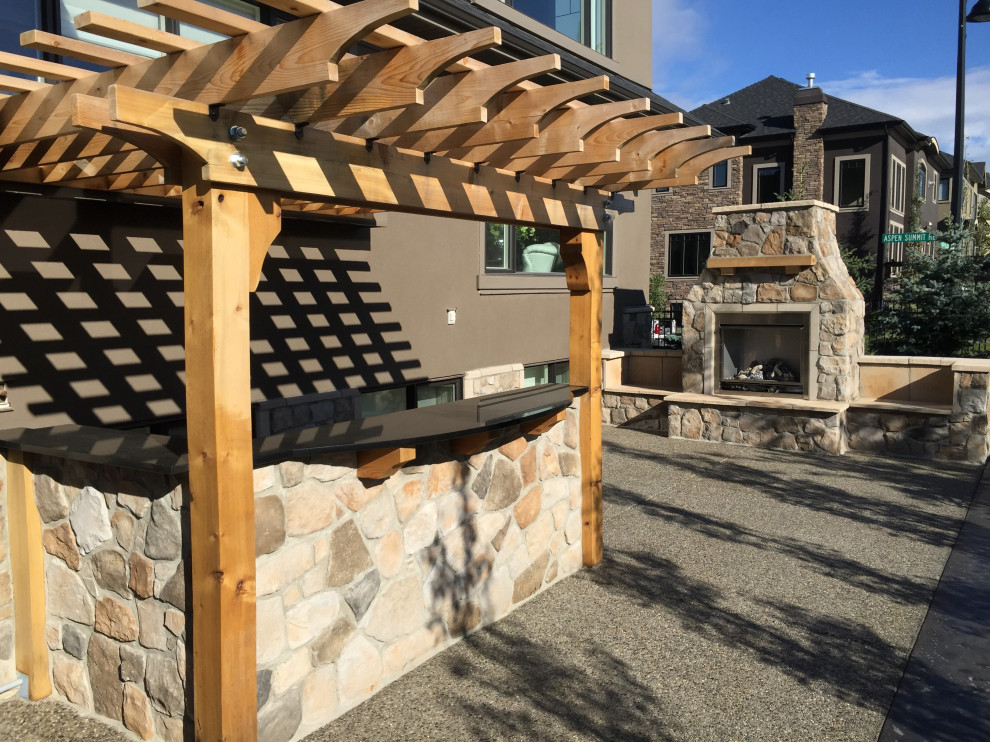 Large courtyard patio in Calgary with an outdoor kitchen, natural stone pavers and a gazebo/cabana.