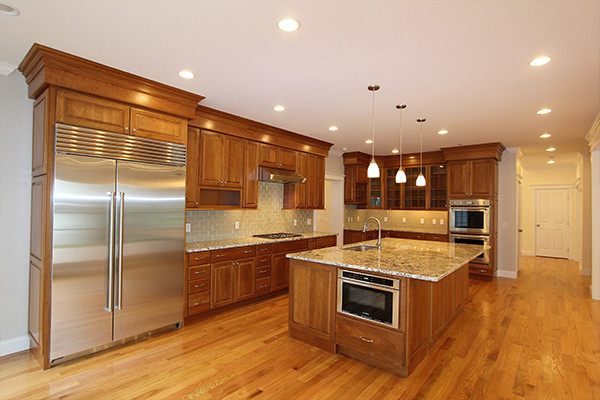 This is an example of a traditional eat-in kitchen in Boston with a drop-in sink, recessed-panel cabinets, medium wood cabinets, medium hardwood floors and with island.