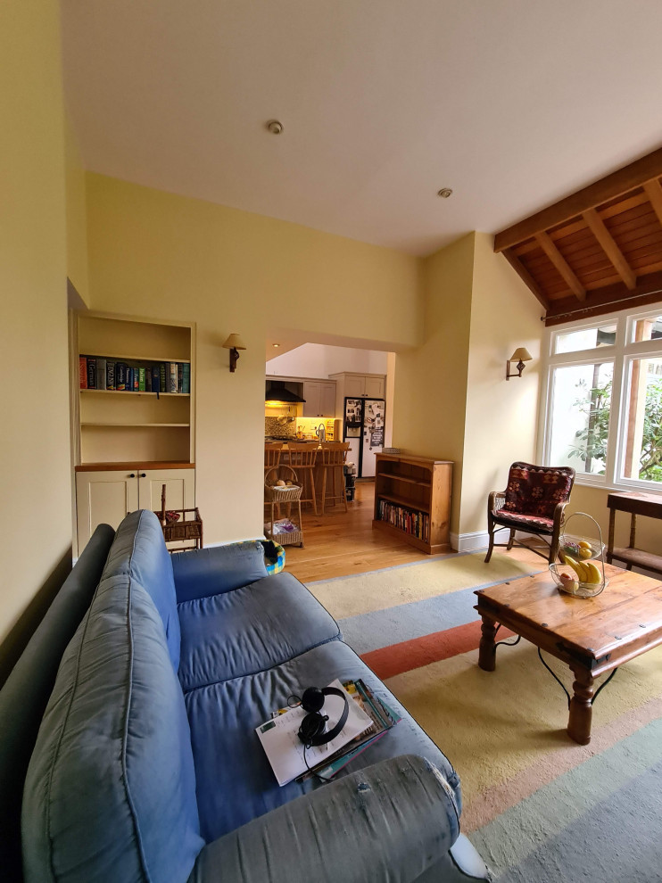 Immagine di un grande soggiorno classico aperto con libreria, pareti gialle, pavimento in legno massello medio, pavimento marrone e soffitto ribassato