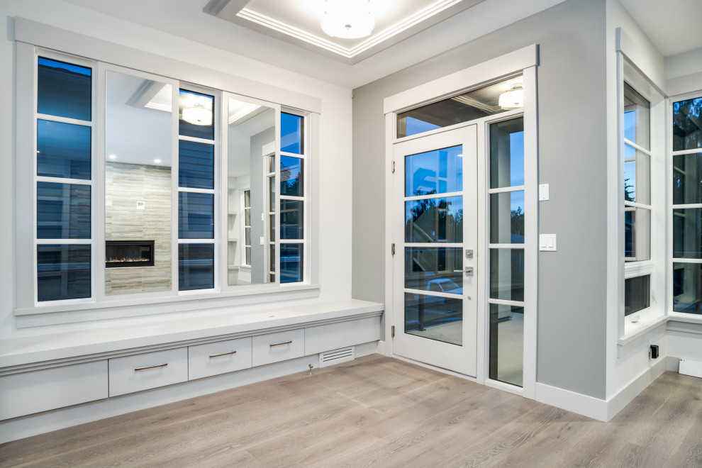 Foyer - mid-sized modern light wood floor foyer idea in Calgary with white walls and a glass front door