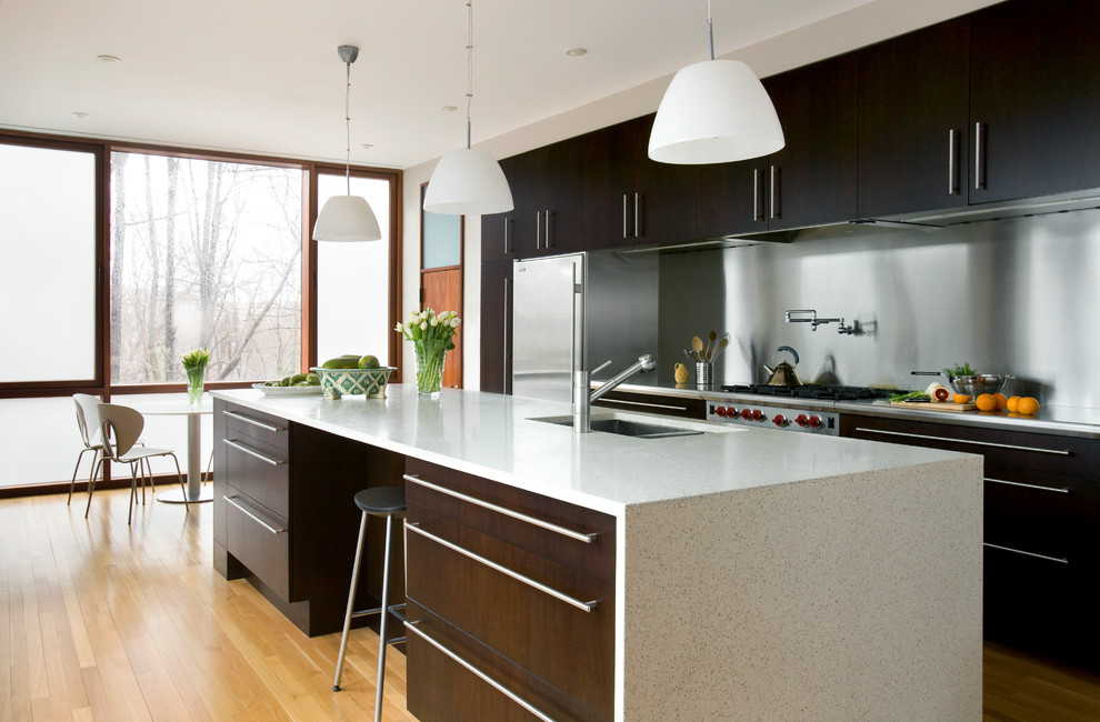 Large contemporary eat-in kitchen in Boston with an undermount sink, flat-panel cabinets, dark wood cabinets, marble benchtops, metallic splashback, stainless steel appliances, light hardwood floors and with island.