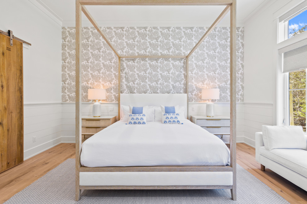 Ejemplo de dormitorio principal marinero grande con paredes blancas, suelo de madera clara y papel pintado