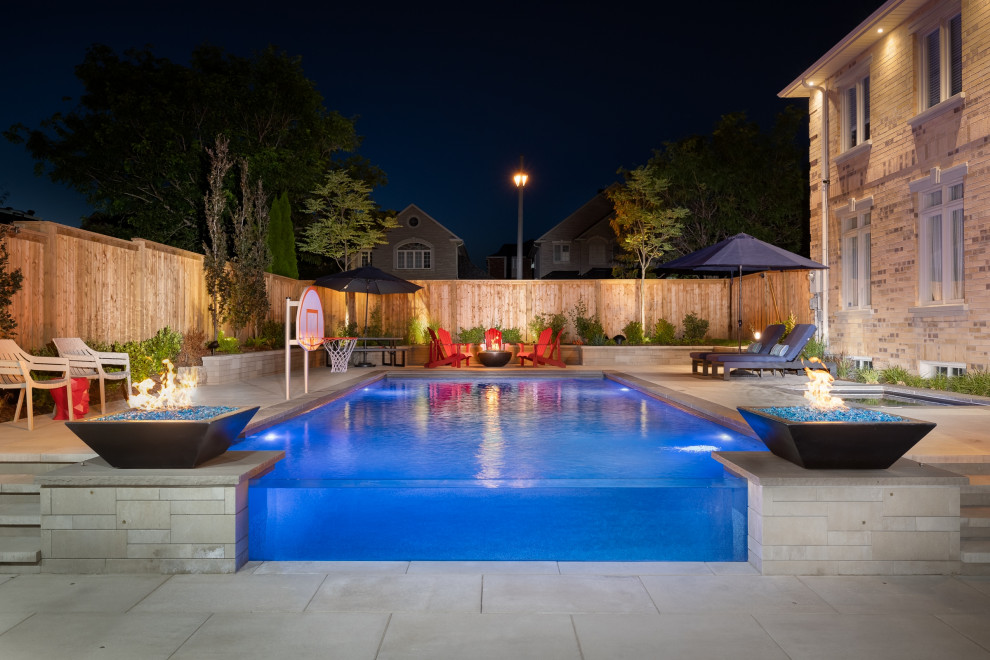 Pool landscaping - mid-sized transitional backyard concrete paver and rectangular infinity pool landscaping idea in Toronto