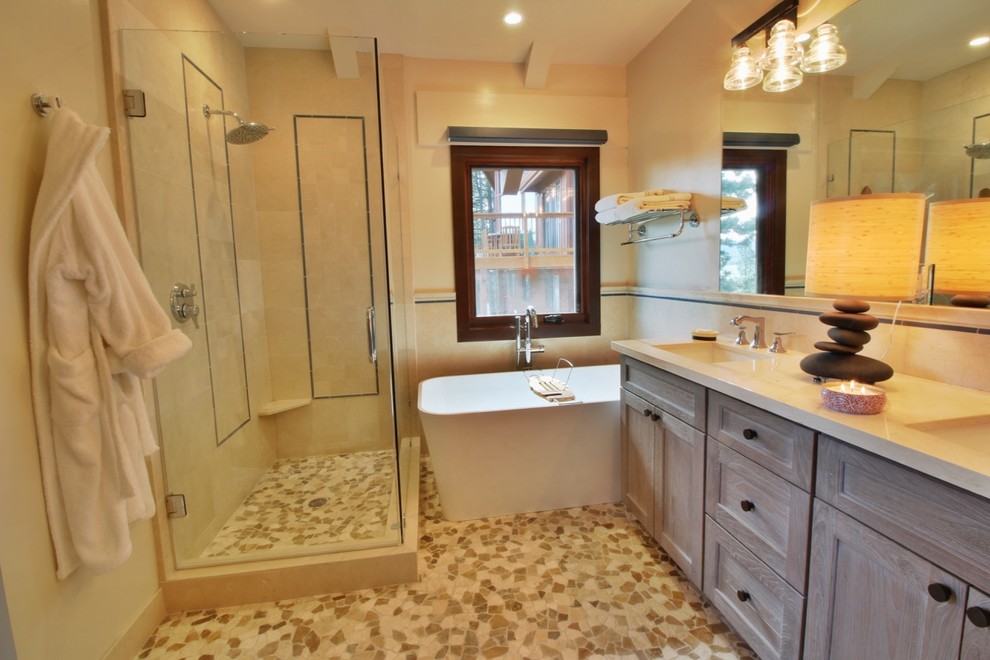 Photo of a mid-sized arts and crafts master bathroom in Sacramento with recessed-panel cabinets, light wood cabinets, a freestanding tub, a corner shower, a two-piece toilet, beige tile, ceramic tile, beige walls, pebble tile floors, an undermount sink, engineered quartz benchtops, multi-coloured floor, a hinged shower door and beige benchtops.