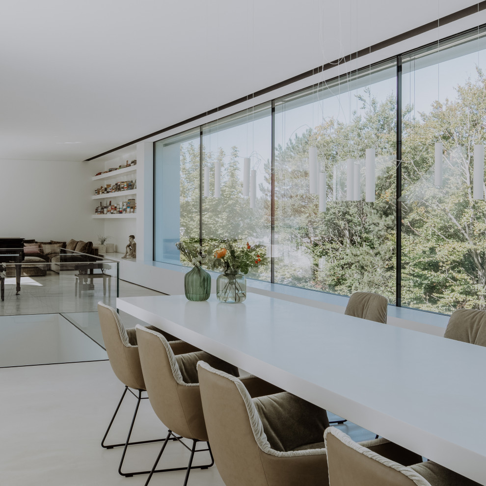 Idee per una grande sala da pranzo aperta verso il soggiorno minimalista con pareti bianche, pavimento in cemento e pavimento grigio