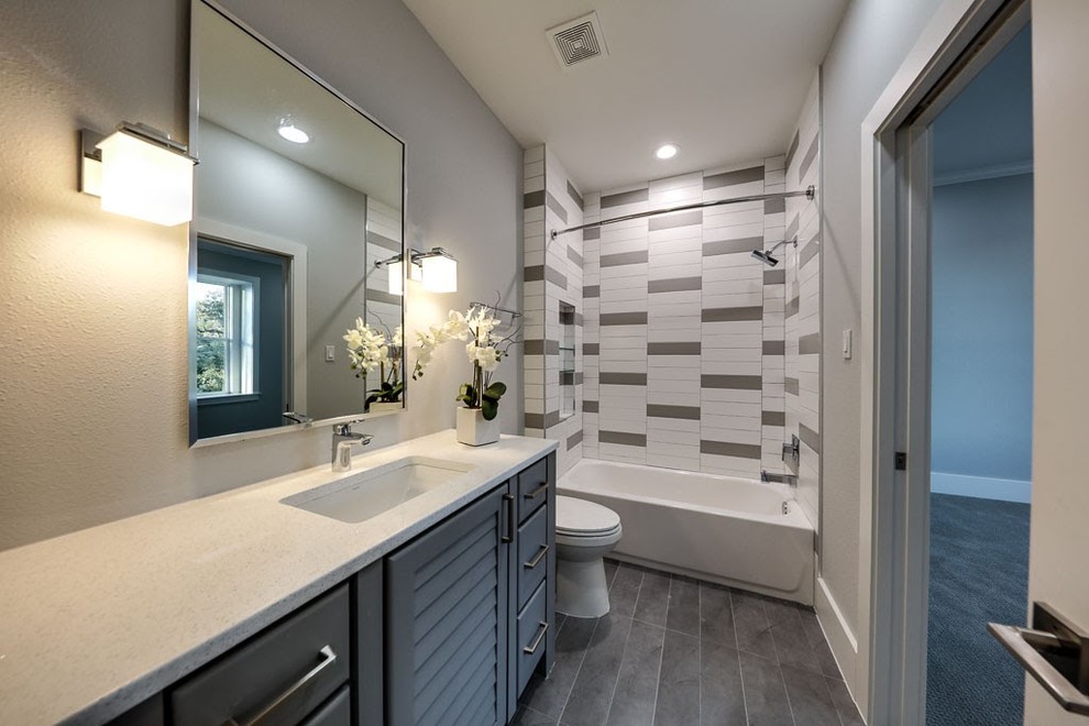 This is an example of a mid-sized contemporary kids bathroom in Houston with furniture-like cabinets, grey cabinets, gray tile, ceramic tile, ceramic floors, quartzite benchtops, an alcove tub, a shower/bathtub combo, a one-piece toilet, grey walls and an undermount sink.
