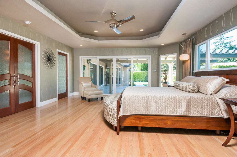 This is an example of a large contemporary master bedroom in San Francisco with beige walls, light hardwood floors and no fireplace.