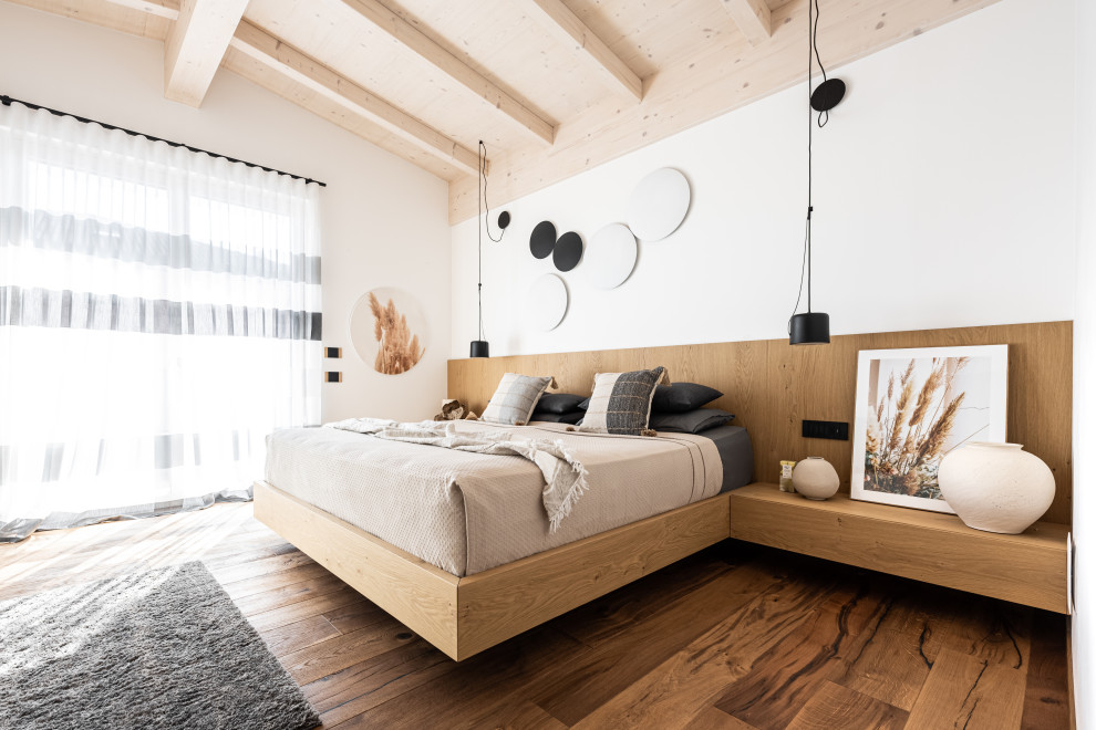 Modern master bedroom in Other with white walls, dark hardwood floors, brown floor, exposed beam and decorative wall panelling.