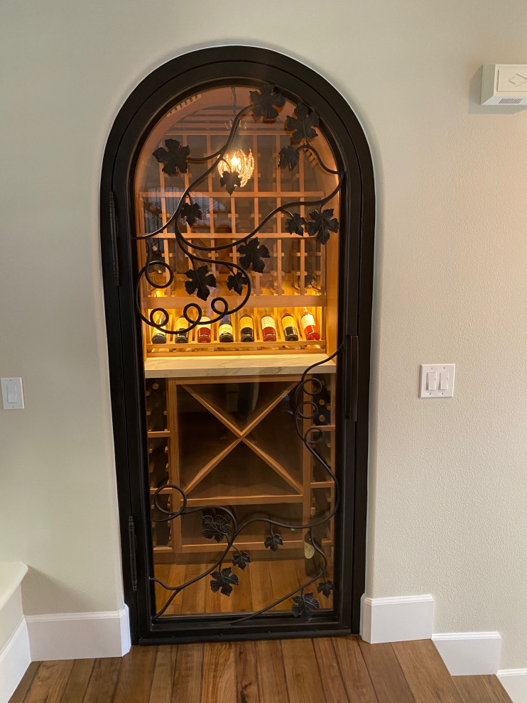 Photo of a small transitional wine cellar in Orange County with dark hardwood floors and display racks.