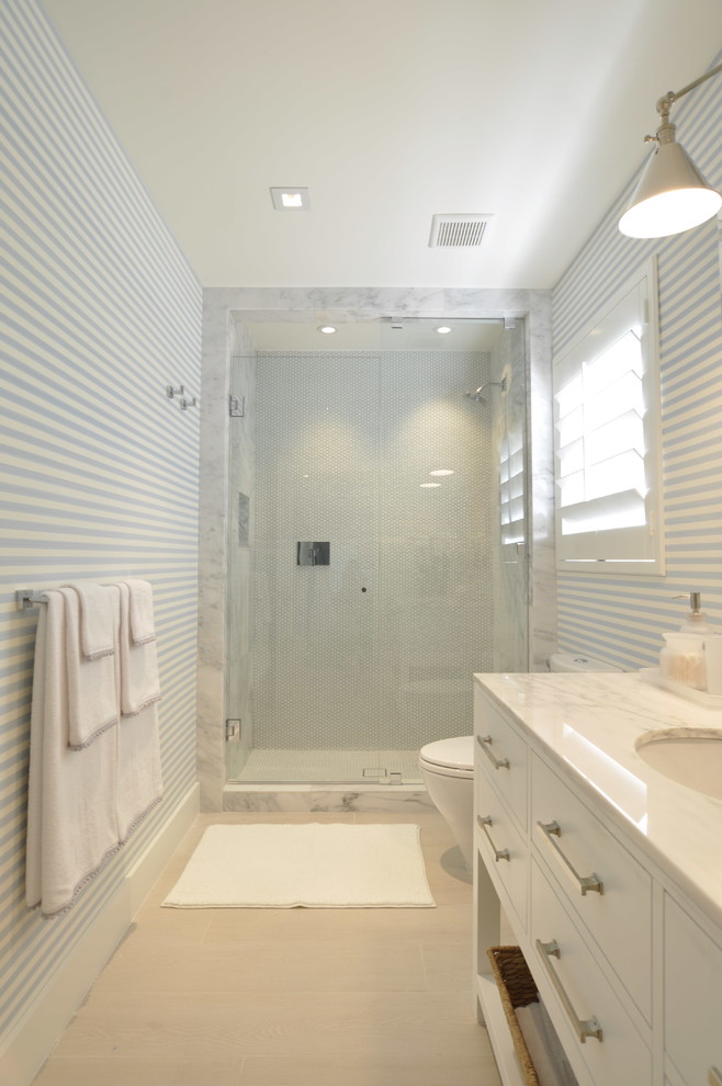 This is an example of a mid-sized transitional 3/4 bathroom in Miami with flat-panel cabinets, white cabinets, an alcove shower, a one-piece toilet, black and white tile, stone slab, white walls, ceramic floors, an undermount sink and marble benchtops.
