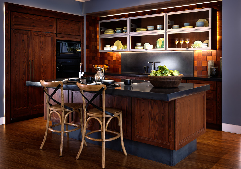 Inspiration for a mid-sized transitional l-shaped eat-in kitchen in Philadelphia with an undermount sink, recessed-panel cabinets, dark wood cabinets, concrete benchtops, black splashback, panelled appliances, with island, timber splashback, medium hardwood floors and brown floor.