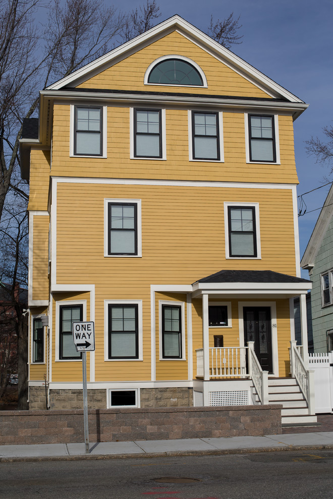 Inspiration for a large transitional three-storey yellow house exterior in Boston with wood siding and a gable roof.