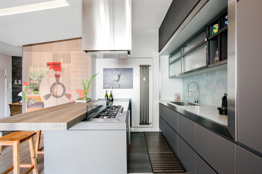 Photo of a mid-sized contemporary galley kitchen in Rome with recessed-panel cabinets, grey cabinets, stainless steel benchtops, blue splashback, ceramic splashback, panelled appliances, dark hardwood floors, a drop-in sink, a peninsula and black floor.