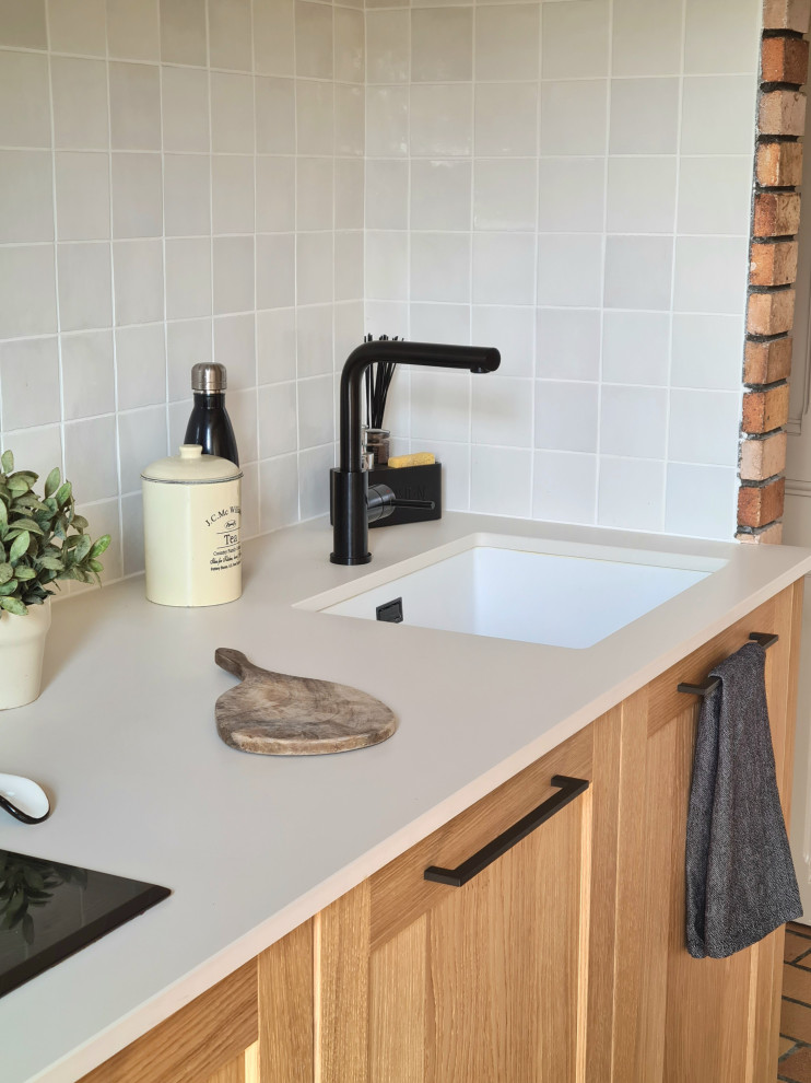 Large country single-wall enclosed kitchen in Lyon with a submerged sink, light wood cabinets, engineered stone countertops, white splashback, terracotta splashback, integrated appliances, terracotta flooring, brown floors, white worktops and exposed beams.