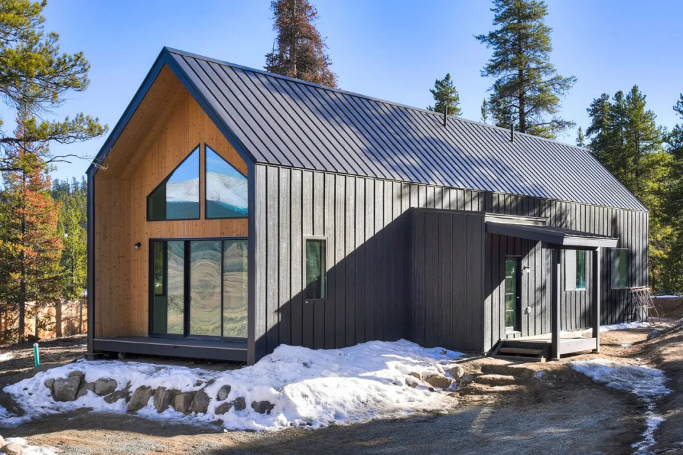 Design ideas for a mid-sized scandinavian two-storey black house exterior in Denver with wood siding, a gable roof, a metal roof, a black roof and board and batten siding.