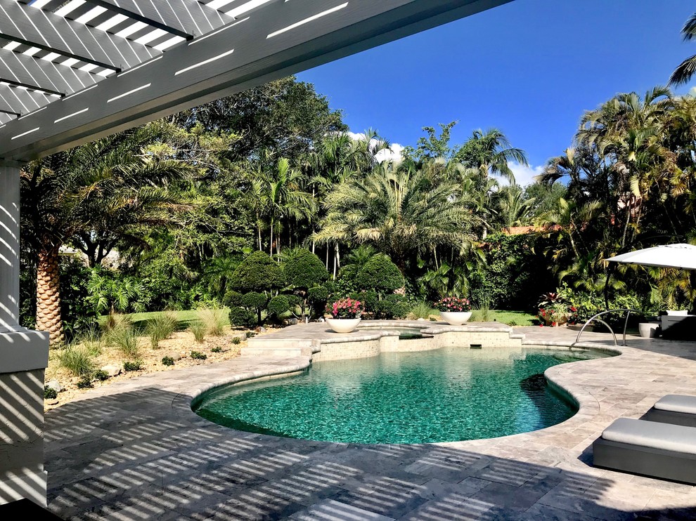 Large mediterranean backyard kidney-shaped pool in Miami with natural stone pavers.
