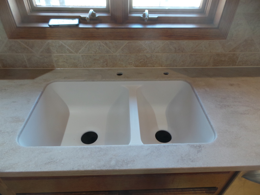Large trendy l-shaped light wood floor and brown floor enclosed kitchen photo with an undermount sink, raised-panel cabinets, medium tone wood cabinets, solid surface countertops, beige backsplash, ceramic backsplash, stainless steel appliances, an island and beige countertops