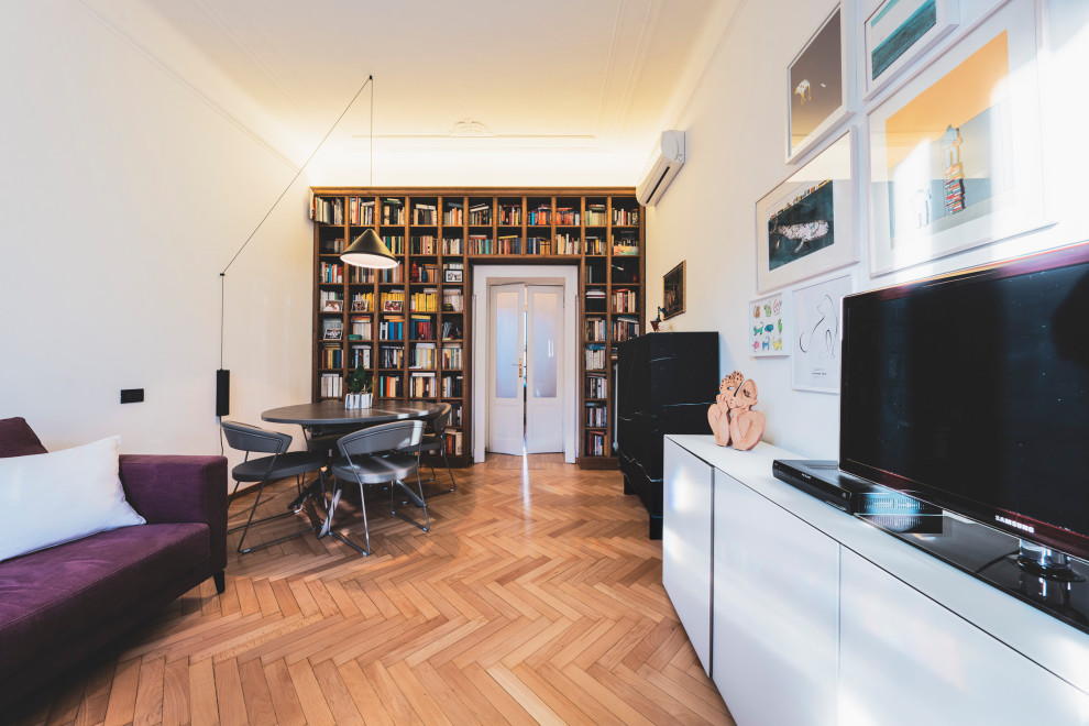 Exemple d'une salle de séjour éclectique de taille moyenne et fermée avec une bibliothèque ou un coin lecture, un mur gris, parquet clair, un téléviseur indépendant et un sol beige.