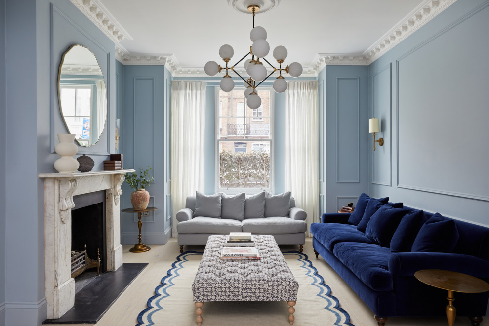Klassisk inredning av ett vardagsrum, med blå väggar, ljust trägolv, en standard öppen spis och beiget golv