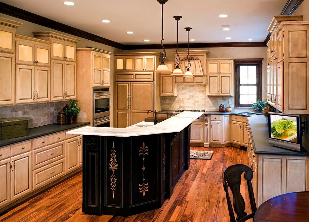 Inspiration for a mid-sized mediterranean galley eat-in kitchen in Minneapolis with an undermount sink, raised-panel cabinets, distressed cabinets, solid surface benchtops, beige splashback, stone tile splashback, panelled appliances, medium hardwood floors and with island.