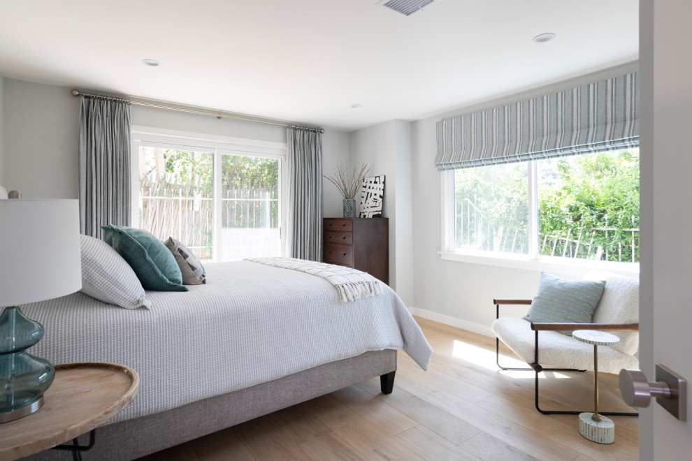 Photo of a large contemporary guest bedroom in Los Angeles with grey walls, light hardwood floors and beige floor.