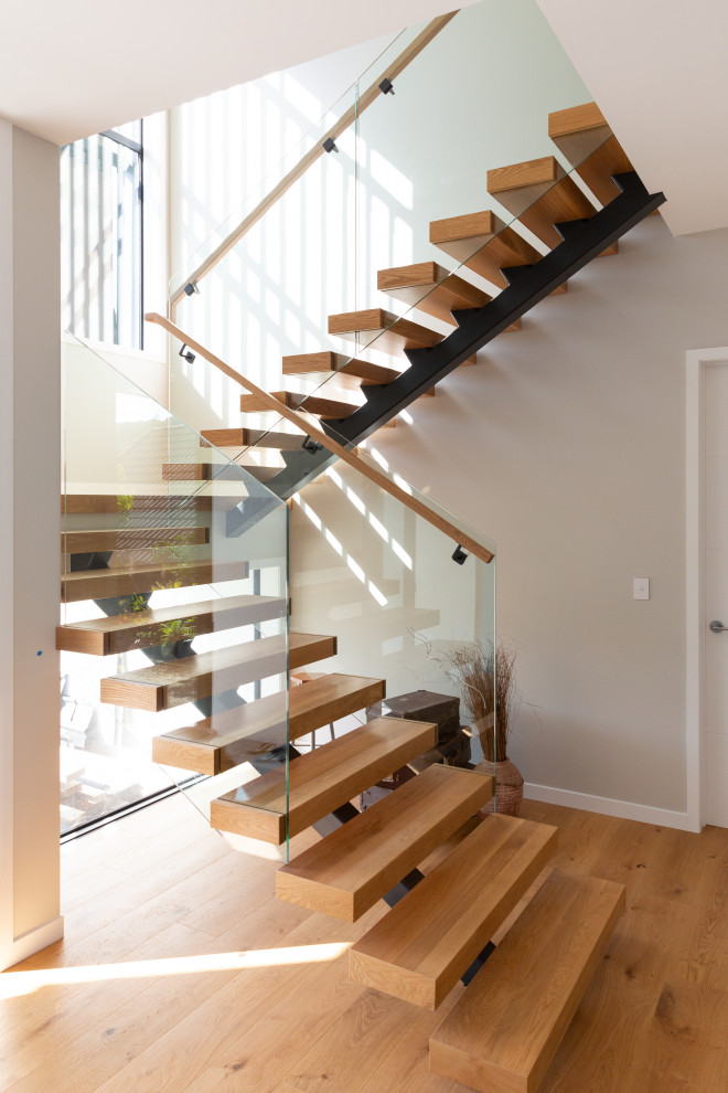 На фото: лестница на больцах, среднего размера в стиле модернизм с деревянными ступенями и перилами из смешанных материалов без подступенок