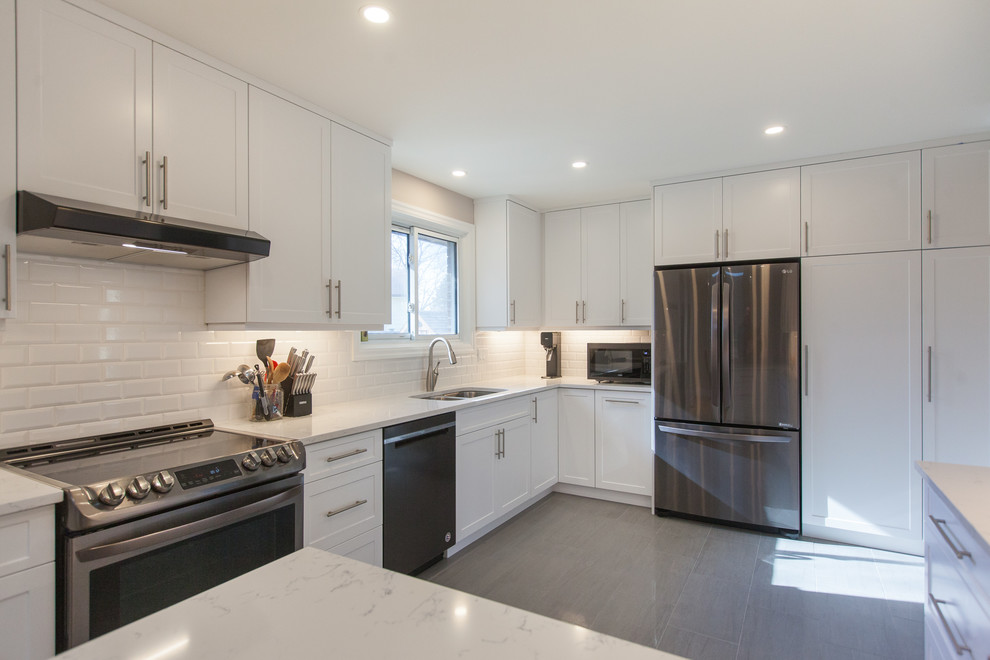 Transitional porcelain tile and gray floor kitchen photo in Toronto with an undermount sink, shaker cabinets, white cabinets, quartzite countertops, white backsplash, porcelain backsplash and stainless steel appliances