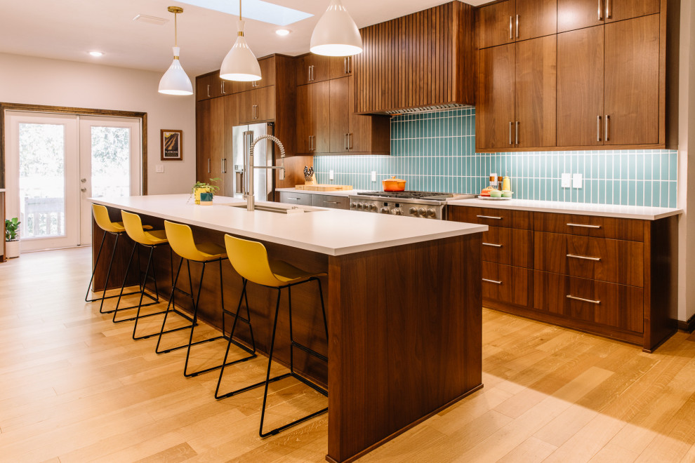 Photo of a large midcentury galley open plan kitchen in Other with an undermount sink, quartz benchtops, blue splashback, porcelain splashback, stainless steel appliances, light hardwood floors, with island, brown floor and white benchtop.