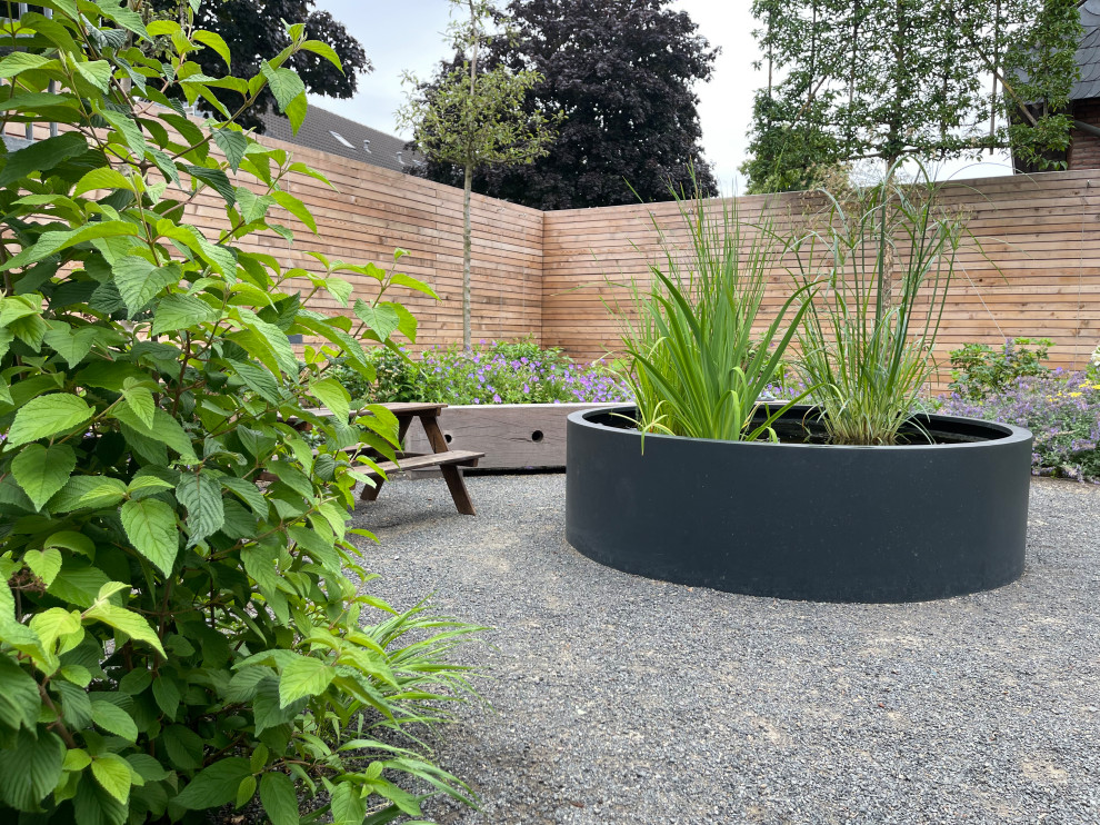 Kleiner Moderner Garten im Sommer, neben dem Haus mit Holzzaun in Köln