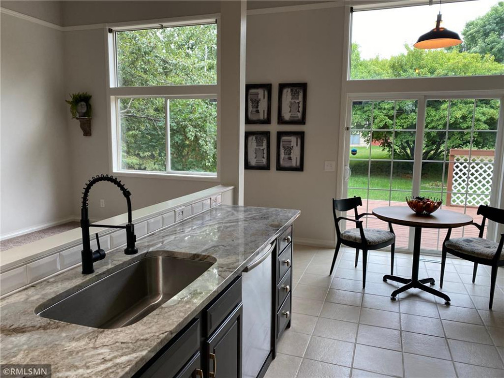 Mid-sized country galley eat-in kitchen in Minneapolis with a single-bowl sink, raised-panel cabinets, black cabinets, marble benchtops, white splashback, ceramic splashback, stainless steel appliances, ceramic floors, with island, beige floor, multi-coloured benchtop and vaulted.