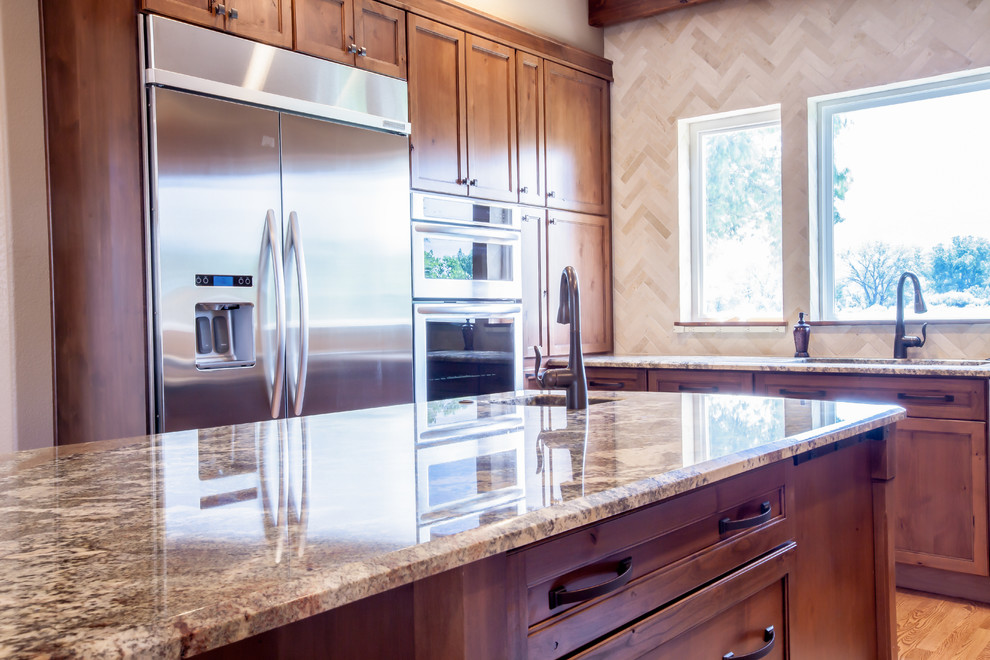 Enclosed kitchen - mid-sized rustic u-shaped medium tone wood floor and brown floor enclosed kitchen idea in Omaha with an undermount sink, shaker cabinets, dark wood cabinets, granite countertops, beige backsplash, travertine backsplash, stainless steel appliances, an island and multicolored countertops