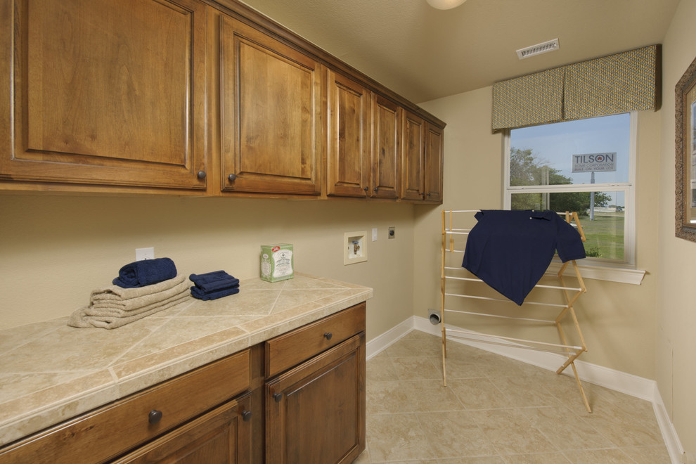 Design ideas for a small traditional single-wall dedicated laundry room in Houston with raised-panel cabinets, medium wood cabinets, tile benchtops, beige walls, porcelain floors, a side-by-side washer and dryer, beige floor and beige benchtop.