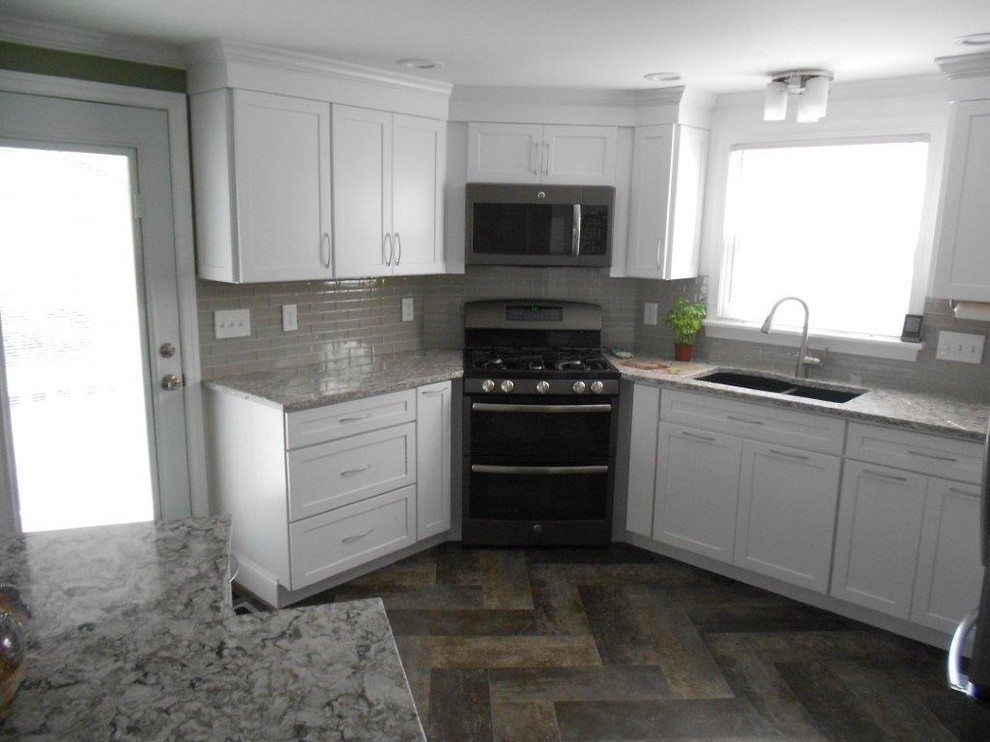 Inspiration for a mid-sized transitional u-shaped eat-in kitchen in Portland Maine with an undermount sink, shaker cabinets, white cabinets, granite benchtops, grey splashback, subway tile splashback, stainless steel appliances, slate floors and with island.